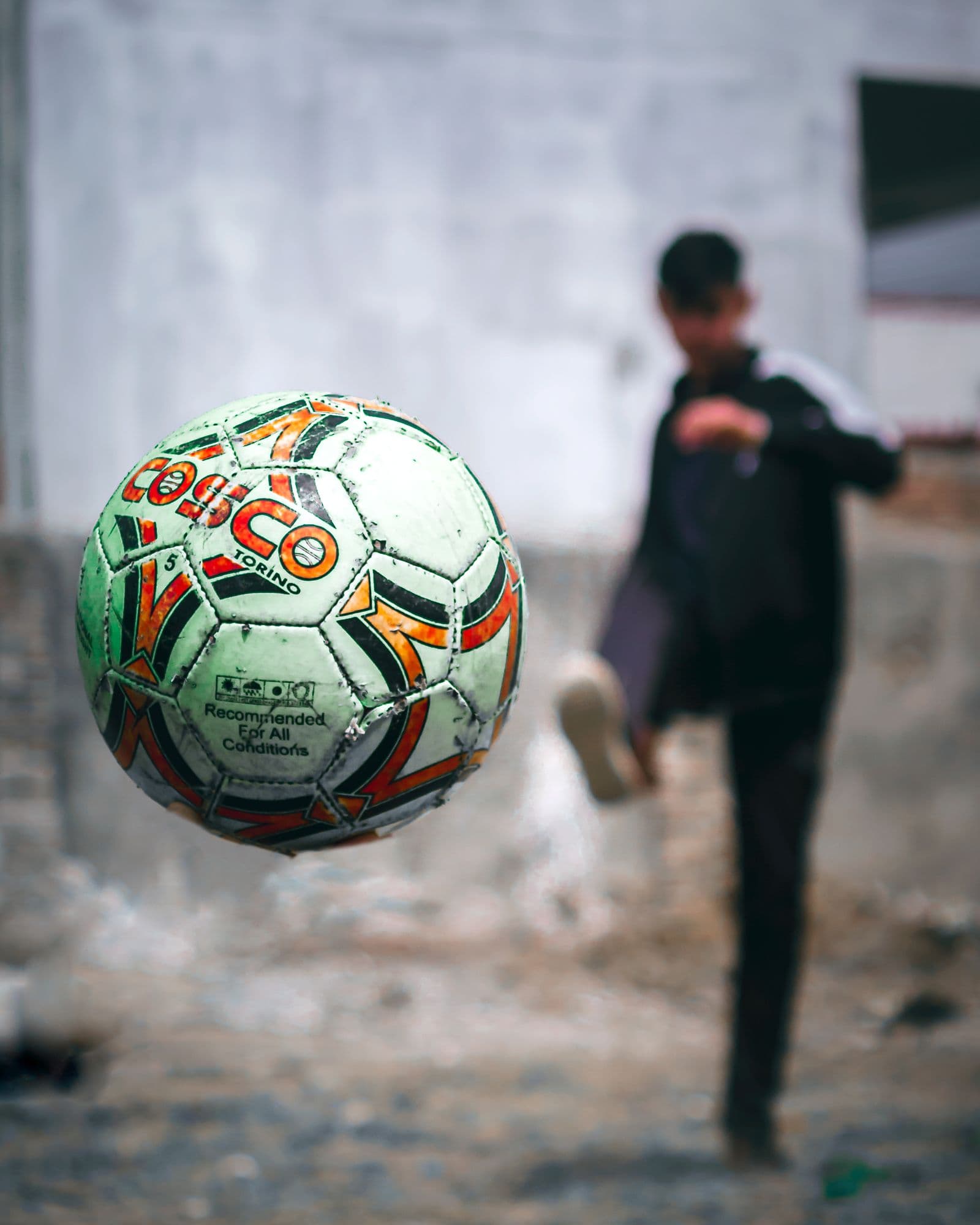 A well-worn Cosco ball mid-kick, street football